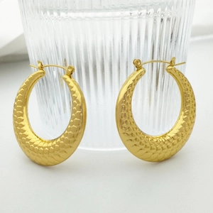 Detail shot of golden U-shaped earrings featuring a luxury snake skin scale texture