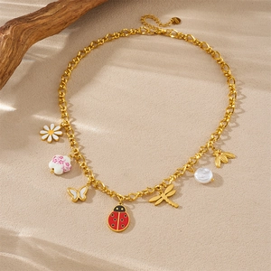 Detailed shot of golden necklace with ladybug, bee, and flower charms on sand surface