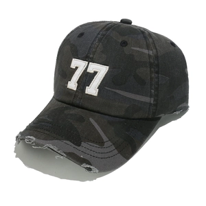 Detail showing distressed holes and embroidery on dark camouflage baseball cap