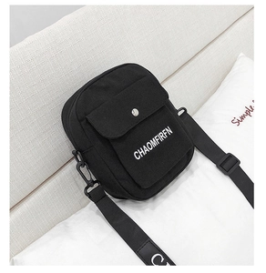 Detail of minimalist black canvas crossbody bag featuring white logo and silver metal buckle