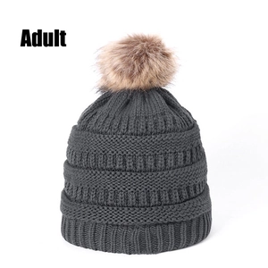 Detailed close-up of dark grey thick knit beanie featuring a brown faux fur pom-pom for adults