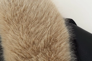 Macro shot of fluffy light brown fur collar and black leather texture on a jacket