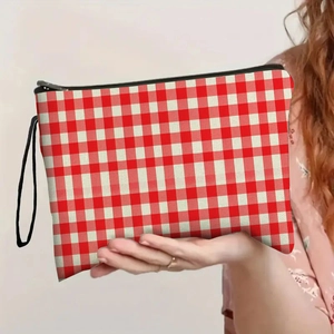 Red and white checkered makeup bag with black wrist strap held by a person