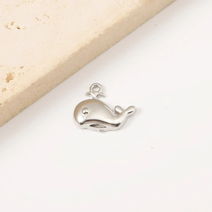 Polished stainless steel whale pendant charm for DIY jewelry on minimalist stone background