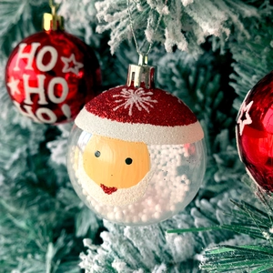 Detail of red festive bauble with HO HO HO text and snowy transparent ornament with Santa