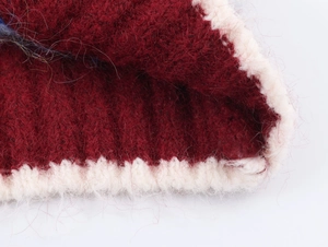Close-up of wine red knitted cardigan featuring white scalloped edges and mohair texture