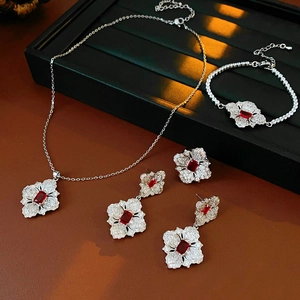 Macro shot of silver flower jewelry set featuring red gems and sparkling clear zircon stones