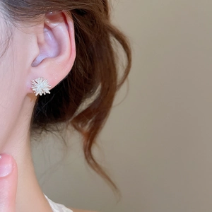 Close-up of elegant silver firework-shaped pearl earrings worn by a model in soft light