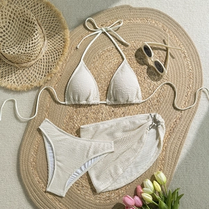 Detail view of white three-piece bikini set with textured seersucker fabric and wrap skirt