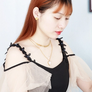 Model wearing a double-layer gold chain necklace with a white shell heart pendant and studs