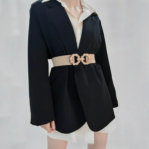 Detail of beige elastic belt with golden twisted knot buckle on a black blazer
