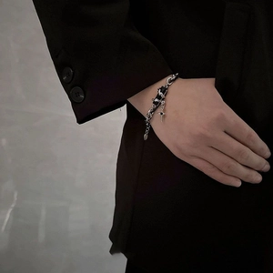 Detail of titanium steel bracelet with cross pendant on model in street style suit