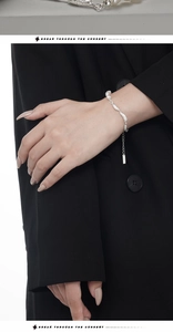 Close-up of irregular silver nuggets and white pearl bracelet on black fabric