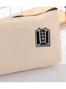 Detail of alien enamel pin with multi-eye totem attached to a white canvas bag