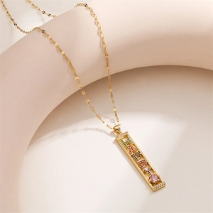 Close-up of golden necklace with colorful HAPPY crystal pendant and pink heart gem