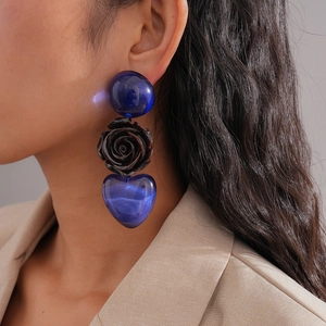 Détail de longues boucles d'oreilles avec cœur en résine bleue et motif de rose