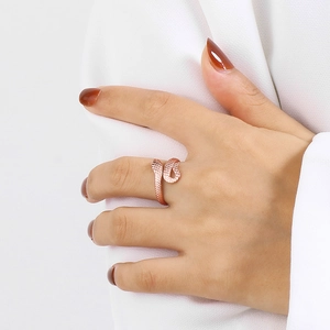 Detail of a rose gold snake ring with scale texture worn by a model on white fabric