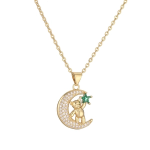 Detailed close-up of a gold crescent moon pendant with a cute bear and green star jewel