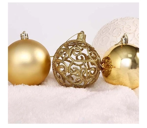 Close-up of gold and white hollow-out Christmas balls on soft white plush background