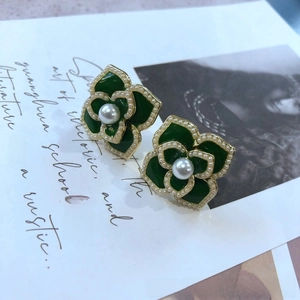Détail des boucles d'oreilles vintage camélia en émail vert avec une perle blanche