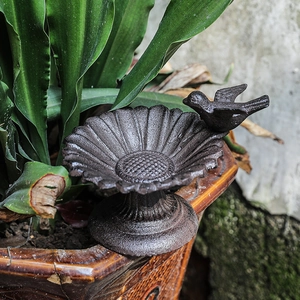 Antique bronze cast iron sunflower bird feeder standing on a decorative garden pot