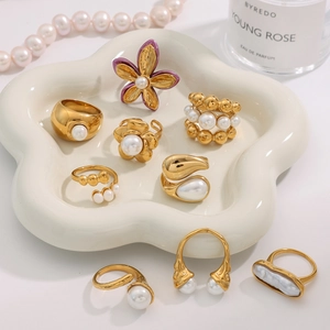 Detailed close-up of 18k gold plated rings and pearl jewelry on a ceramic cloud tray