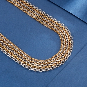 Detailed shot of layered gold and silver stainless steel O-chains on dark blue background