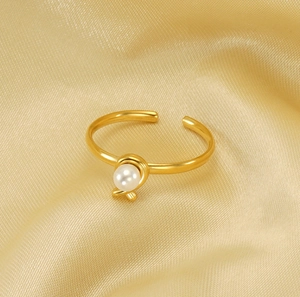 Detailed view of adjustable gold pearl ring on elegant champagne silk fabric background