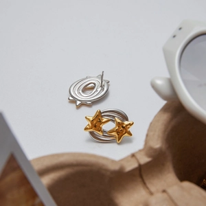 Close-up of gold and silver star earrings on white background with minimalist props