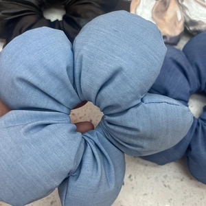 Elegant light blue fabric floral scrunchie shown in hand with multi-color options