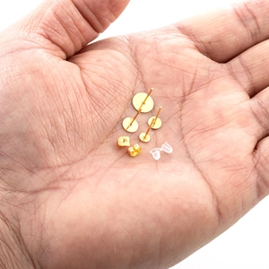 Set di perni per orecchini dorati con base piatta e chiusure mostrate sulla mano