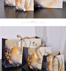 Detail of marble pattern gift bags in black, white, and gold with ribbon handles