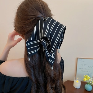 Détail d'une pince à cheveux à nœud rayé noir et blanc avec pendentif perle goutte
