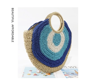 Detail of round straw handbag with blue tricolor woven pattern and circular handles