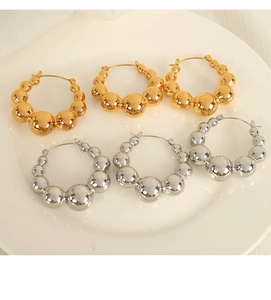 Detail of minimalist beaded hoop earrings in gold and silver finish on white tray