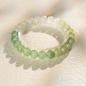 Macro shot of 10mm gradient green jade beads bracelet with artistic floral shadow detail