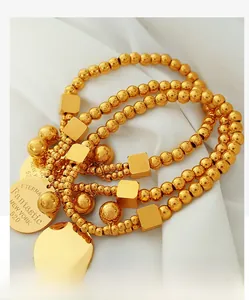 Detailed close-up of 18k gold beads and square charms on elastic strand bracelet