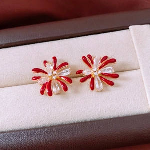 Macro detail of red enamel flower earrings with gold plating and white zircon crystals