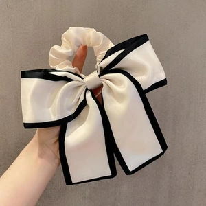 Elegant large cream satin bow hair tie with black trim for low ponytail hairstyles