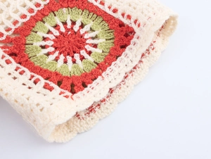 Detailed close-up of handmade crochet knit pattern with red and green floral embroidery