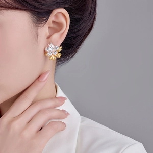 On-ear view of dual-tone flower earrings with silver and gold petals on model