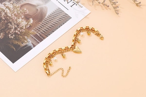 Détail du bracelet double couche avec cœur doré, perles blanches et billes métalliques