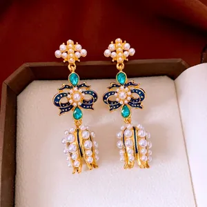 Vintage style bow pearl earrings with green gemstones and blue enamel in jewelry box