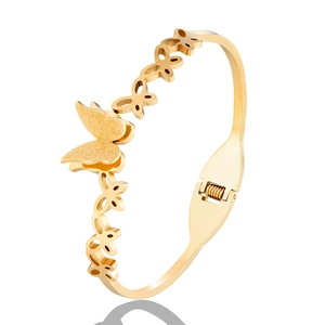 Detailed shot of hinged gold butterfly bracelet featuring frosted and cutout textures