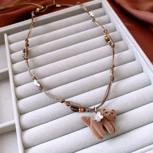 Détail du collier en perles d'œil de tigre avec pendentif chat sur plateau à bijoux