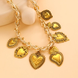 Detail der goldenen Vintage-Halskette mit Sacred-Heart-Anhängern und weißen Fadenakzenten
