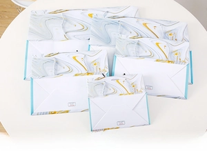 Macro shot of flat-folded marble pattern gift bags showing space-saving storage design