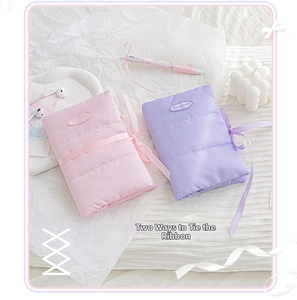 Detailed view of quilted cotton notebook covers in pink and purple with ribbon ties