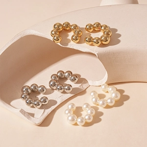 Minimalist C-shaped ear cuffs set in gold and silver metal with white faux pearls