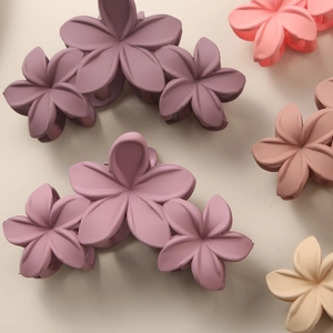 Macro detail of matte floral claw clips in purple, pink, and beige Morandi shades